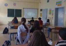 sala lekcyjna, na ekranie jest prezentowany film edukacyjny, grupa uczniów siedzi w ławkach i ogląda projekcję