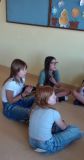 grupa uczniów w Sali lekcyjnej siedzi na podłodze i prowadzi ożywioną rozmowę