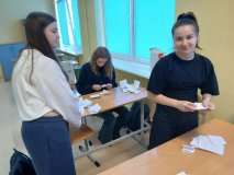 W pustej sali lekcyjnej znajdują się trzy uczestniczki koła SU, które segregują i liczą głosy oddane przez uczniów w wyborach do Rady Samorządu Uczniowskiego. Między nimi, na ławkach szkolnych leżą karty do głosowania.