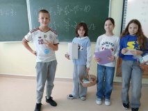 Trzy uczestniczki koła SU wraz z uhonorowanym „Najsympatyczniejszym Chłopakiem w klasie”, który na szyi ma zawieszony okrągły, niebieski medal oraz wykonuje radosny gest ręką. Wszyscy są w pogodnych nastrojach.