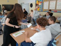 W przestronnej sali trzy przedstawicielki SU rozdają uczniom jednej z klas karty do głosowania w wyborach do Rady Samorządu Uczniowskiego.