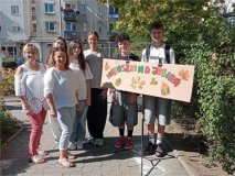 Grupa uczniów Samorządu Uczniowskiego oraz ich opiekunki stoją na zewnątrz przy tablicy z napisem „Miętoszki na jesień”. W tle widać budynki i drzewa, a uczestnicy uśmiechają się do zdjęcia w słoneczny dzień.