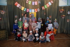 Pamiątkowe zdjęcia klas 1a, 1b, 1c, 1d, 1e, 1f z Pluszowym Misiem na tle dekoracji z napisem „Dzień Pluszowego Misia”.