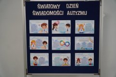 Tablica informacyjna z napisem „Światowy Dzień Świadomości Autyzmu”, na której umieszczono plakaty z ilustracjami i krótkimi informacjami dotyczącymi tego zaburzenia.