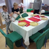 Dwóch chłopców uzupełnia nakrycie stołu o serwetki.