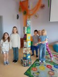 Grupa uczniów prezentuje zbudowaną z książek wieżę, która jest od nich wyższa „o głowę”.