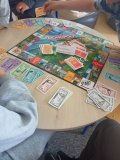 grupa Uczniów przy okrągłym stoliku gra w „Monopoly Płock”