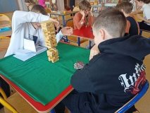 przy dwóch stolikach siedzą Uczniowie, dwoje z nich gra w Jengę, dwóch w warcaby