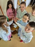 grupa Uczniów z klasy trzeciej  trzyma dłonie na magicznej, świecącej kuli, która służyła do zabawy we wróżby