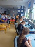 czytelnia biblioteki, grupa Uczniów siedzi przy stanowiskach z komputerami i rozwiązuje quiz, Uczeń w stroju Harrego Pottera nadzoruje wykonanie zadania, w tle na projektorze zdjęcie starej, stylowej biblioteki