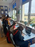 czytelnia biblioteki, grupa Uczniów siedzi przy stanowiskach z komputerami i rozwiązuje quiz, Uczeń w stroju Harrego Pottera nadzoruje wykonanie zadania