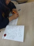 Uczennica siedzi przy stole w czytelni i w skupieniu rozwiązuje test wiedzy o zaklęciach