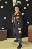 Uczeń pozuje do zdjęcia na tle czarnej ścianki z napisem „Ogólnopolski Tydzień Bibliotek”, „Hogwartowy challenge”, jest w stroju Harrego Pottera, w wyciągniętej ręce ma różdżkę