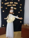 Uczennica pozuje do zdjęcia na tle czarnej ścianki z napisem „Ogólnopolski Tydzień Bibliotek”, „Hogwartowy challenge”, jest przebrana za sowę - bohaterkę z serii książek o Harrym Potterze , ma białą koszulkę i długa białą spódnicę, maskę zasłaniającą pół twarzy oraz skrzydła