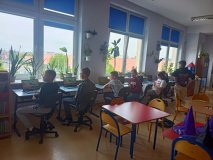 grupa Uczniów siedzących przy stanowiskach komputerowy rozwiązuje quiz