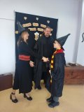 kobieta i mężczyzna – bibliotekarze w strojach czarodziejów wręczają nagrodę i gratulują Uczniowi, który brał udział w konkursie na najciekawsze przebranie w stylu bohaterów książek o Harrym Potterze, Uczeń jest przebrany za Harrego Pottera