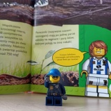 Praca uczniów – figurka Lego na tle fragmentu książki „Lego”.