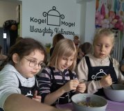 Trzy uczennice z zaangażowaniem mieszają w miseczkach produkty potrzebne do przygotowania zdrowych ciasteczek owsianych.