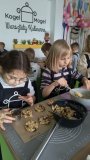 Dziewczynki formują masę owsianą za pomocą odpowiedniej foremki, przygotowując ją do dalszego etapu – upieczenia ciasteczek.