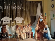 Na tle głównej dekoracji, przed szopką, siedzi Maryja trzymająca Dzieciątko oraz Józef. Po prawej stronie szopki, na niskiej ławeczce, siedzi czterech pastuszków.