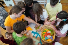 Grupa uczniów wykonuje pracę plastyczną z kolorowych kartek.