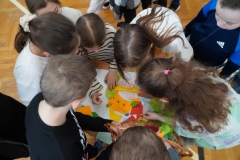 Grupa uczniów wykonuje pracę plastyczną z kolorowego papieru.