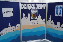 Niebieska tablica dekoracyjna z dużym napisem „DZIĘKUJEMY”, logo „Entelo”, herbem Wisły Płock oraz papierową makietą białego zamku i kościołów nad wodą.