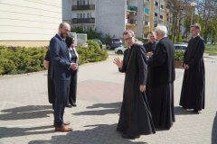 Na zdjęciu widzimy dwóch uśmiechniętych mężczyzn: ks. Biskupa Mirosława Milewskiego  oraz p. Przemysława Zielińskiego. W tle znajdują się trzej księża oraz dyrekcja szkoły. 