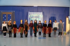 Licząca dwanaście osób grupa teatralna, ustawiona na tle dekoracji, kłania się widzom, kończąc przedstawienie.