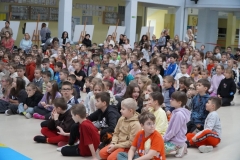 Grupa nauczycieli, uczniów tworzących widownię oraz aktorów ogląda prezentację multimedialną wyświetlaną na jednej ze ścian forum. Jej treść omawia koordynator spotkania- p. Anna Kowalska.
