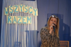 Grupa nauczycieli, uczniów tworzących widownię oraz aktorów ogląda prezentację multimedialną wyświetlaną na jednej ze ścian forum. Jej treść omawia koordynator spotkania- p. Anna Kowalska.