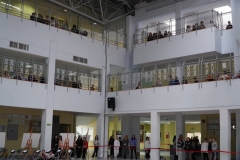 Uczniowie klas IV-VIII, stojący na rożnych poziomach budynku, obserwują wyświetlaną na forum szkoły prezentację multimedialną.