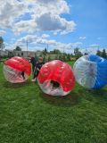 Uczniowie bawią się w bomber ball – dynamiczna scena na trawie.