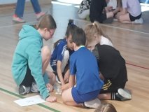 Piątka Uczniów siedzi na podłodze i układa puzzle.