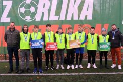 Na tle zielonego baneru z napisem: „Z Orlika na Stadion” stoi ośmioosobowa reprezentacja szkoły chłopców w roczniku 2011 wraz z trenerem Sebastianem Załęskim i przedstawicielem PZPN.