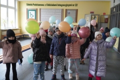  Przedszkolaki żegnają się ze szkołą machając kolorowymi balonami.
