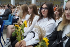 Ósmoklasiści siedzący na forum szkoły, przysłuchujący się przedstawieniu.