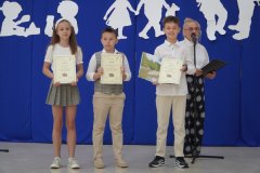 Szczęśliwa trójka laureatów klas trzecich Szkolnej Ligi Przedmiotowej z języka polskiego trzymająca w dłoniach książki i dyplomy za udział w konkursie.