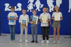 Szczęśliwa piątka laureatów klas trzecich Szkolnej Ligi Przedmiotowej z matematyki trzymających w dłoniach książki i dyplomy za udział w konkursie.