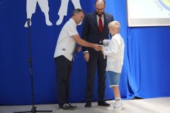 Nauczyciel pan Mariusz Łakomski wraz z przewodniczącym Rady Rodziców panem Przemysławem Zielińskim wręczają uczniowi nagrodę książkową i dyplom za udział w turnieju szachowym.