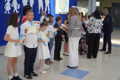 Uczniowie klasy 3a otrzymują na forum szkoły pamiątkowe książki i dyplomy z okazji ukończenia pierwszego etapu edukacyjnego.
