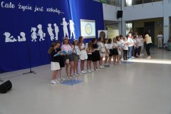 Uczniowie klasy 3c otrzymują na forum szkoły pamiątkowe książki i dyplomy z okazji ukończenia pierwszego etapu edukacyjnego.