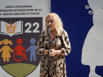 Na tle logo Szkoły widać Panią Dyrektor Marlenę Błachowicz, podczas Jej wystąpienia.