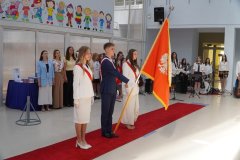 Uczniowie klas ósmych z dumą prezentują sztandar szkoły.