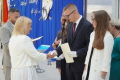 Na scenie stoi Pani Dyrektor i wręcza podziękowania reprezentantom byłego pocztu sztandarowego.