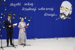 Na scenie stoją prowadzący uroczystość zakończenia roku szkolnego klas ósmych- Nauczyciel i Uczeń.