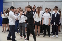 Na scenie stoją Uczniowie klasy 8e i śpiewają piosenkę pt. ,,Na szczycie góry’’.