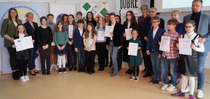 Zdjęcie grupowe wszystkich lureatów oraz nauczycieli na tle banerów szkoły, Książnicy Płockiej oraz Stowarzszenia Trakt.