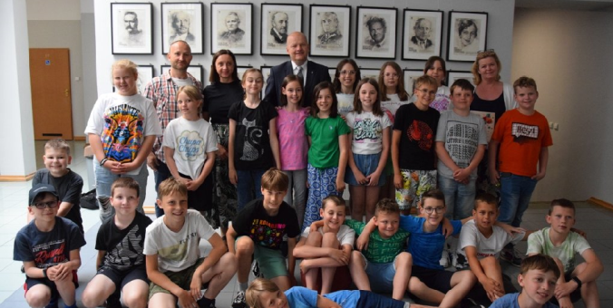 Zdjęcie uczniów klasy 4c z Prezydentem Miasta na tle zdjęć honorowych obywateli Miasta Płocka.