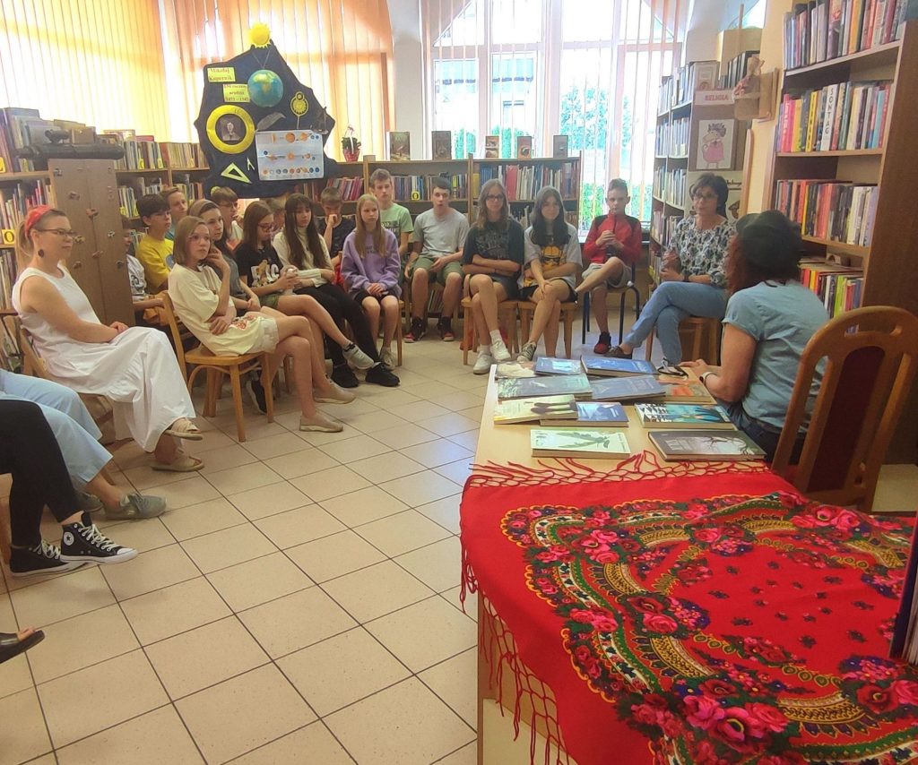 Uczniowie z klasy 6e siedzą i słuchają z zaciekawieniem Barbary Kosmowskiej.